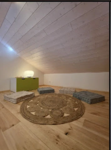Espace de repos aménagé sur la mezzanine, avec des coussins et un tapis rond tressé